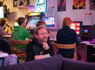 Lächelnde Person im Vordergrund und im Hintegrund Arcade Automat