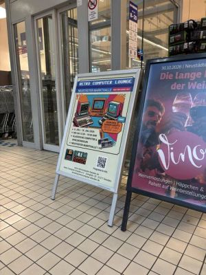 Zwei Werbeaufsteller für Retro-Computer-Lounge und Weinverkostung vor dem Eingang einer Markthalle.