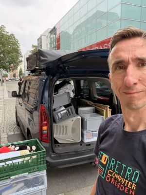Mann mit „Retro Computer Dresden“-Shirt vor Van beladen mit alter Computertechnik.