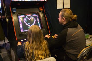 Zwei Personen spielen gemeinsam an einem Arcade-Automaten