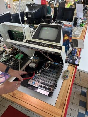 Geöffneter Commodore CBM Computer mit freiliegender Platine und Smartphone in der Hand davor.