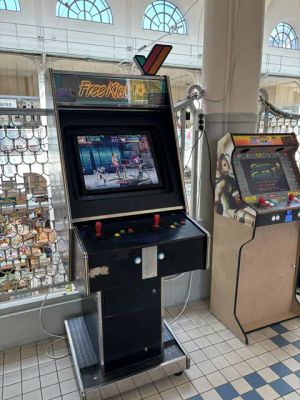 Retro-Arcade-Automat „Free Kick“ mit roten Joysticks und Kampfspiel-Anzeige in einem hellen Raum.